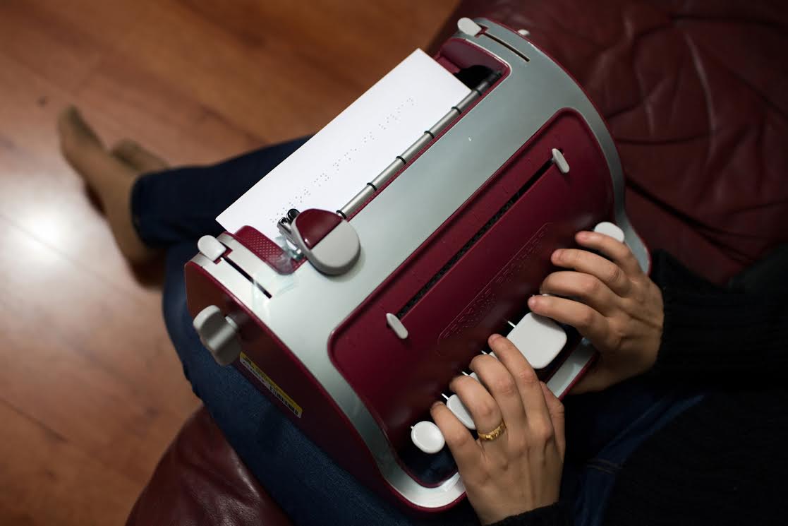 Lulu Al-Aydi, 25, shows off her new Braille typewriter, given to her by the Swedish government, in Fagersta, Sweden, Nov. 1, 2014. Lulu, an Arabic literature student from Yarmouk near Damascus, fled with her father Seif to Greece in early 2014, then managed to make it to Sweden. Lulu has been blind since birth and chose Sweden because it has generous social services and is open-minded. Image by Holly Pickett. Sweden, 2014.
