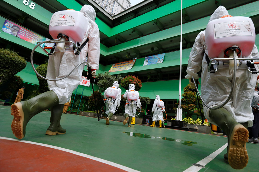 Volunteers from Indonesia's Red Cross prepare to spray disinfectant at a school closed amid the spread of coronavirus (COVID-19) in Jakarta. Image by REUTERS/Willy Kurniawan. Indonesia, 2020. Volunteers from Indonesia's Red Cross prepare to spray disinfectant at a school closed amid the spread of coronavirus (COVID-19) in Jakarta. Image by REUTERS/Willy Kurniawan. Indonesia, 2020.