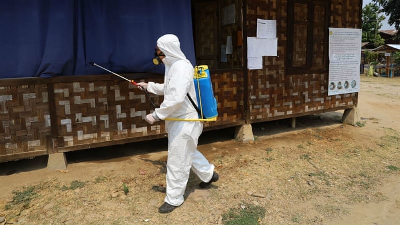 A volunteer from the Kachin State COVID-19 Prevention network sprays disinfectant at a camp in Myitkyina, Kachin state. Image courtesy Al Jazeera. Myanmar, 2020. A volunteer from the Kachin State COVID-19 Prevention network sprays disinfectant at a camp in Myitkyina, Kachin state. Image courtesy Al Jazeera. Myanmar, 2020.