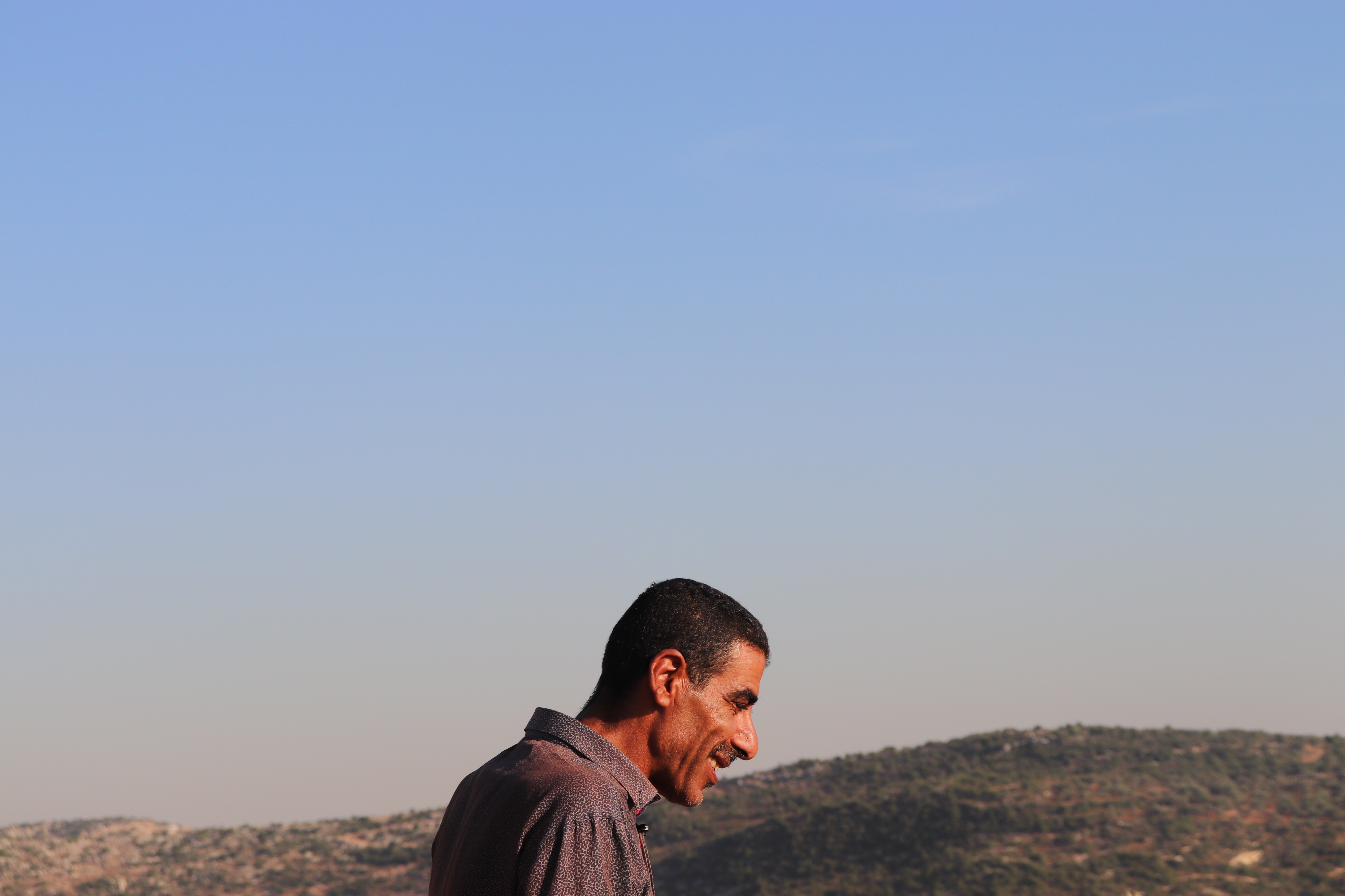 A farmer in Burqin, an agricultural village in the West Bank, stands on what's left of his olive groves. In January 2019, he received an order from the Israeli Civil Administration to uproot half his trees. A few weeks later, the remainder were razed. Image by Carly Graf. West Bank, 2019. A farmer in Burqin, an agricultural village in the West Bank, stands on what's left of his olive groves. In January 2019, he received an order from the Israeli Civil Administration to uproot half his trees. A few weeks later, the remainder were razed. Image by Carly Graf. West Bank, 2019.