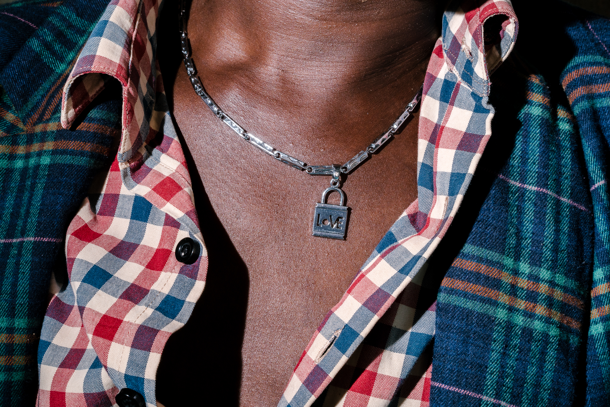 Sweet Love, a transgender woman and the chairperson of Children of the Sun, poses for a portrait with a necklace from her boyfriend. She sits at the Children of the Sun safe house, which shelters at-risk and in-need LGBTQ+ persons. Image by Jake Naughton. Uganda, 2017. Sweet Love, a transgender woman and the chairperson of Children of the Sun, poses for a portrait with a necklace from her boyfriend. She sits at the Children of the Sun safe house, which shelters at-risk and in-need LGBTQ+ persons. Image by Jake Naughton. Uganda, 2017.