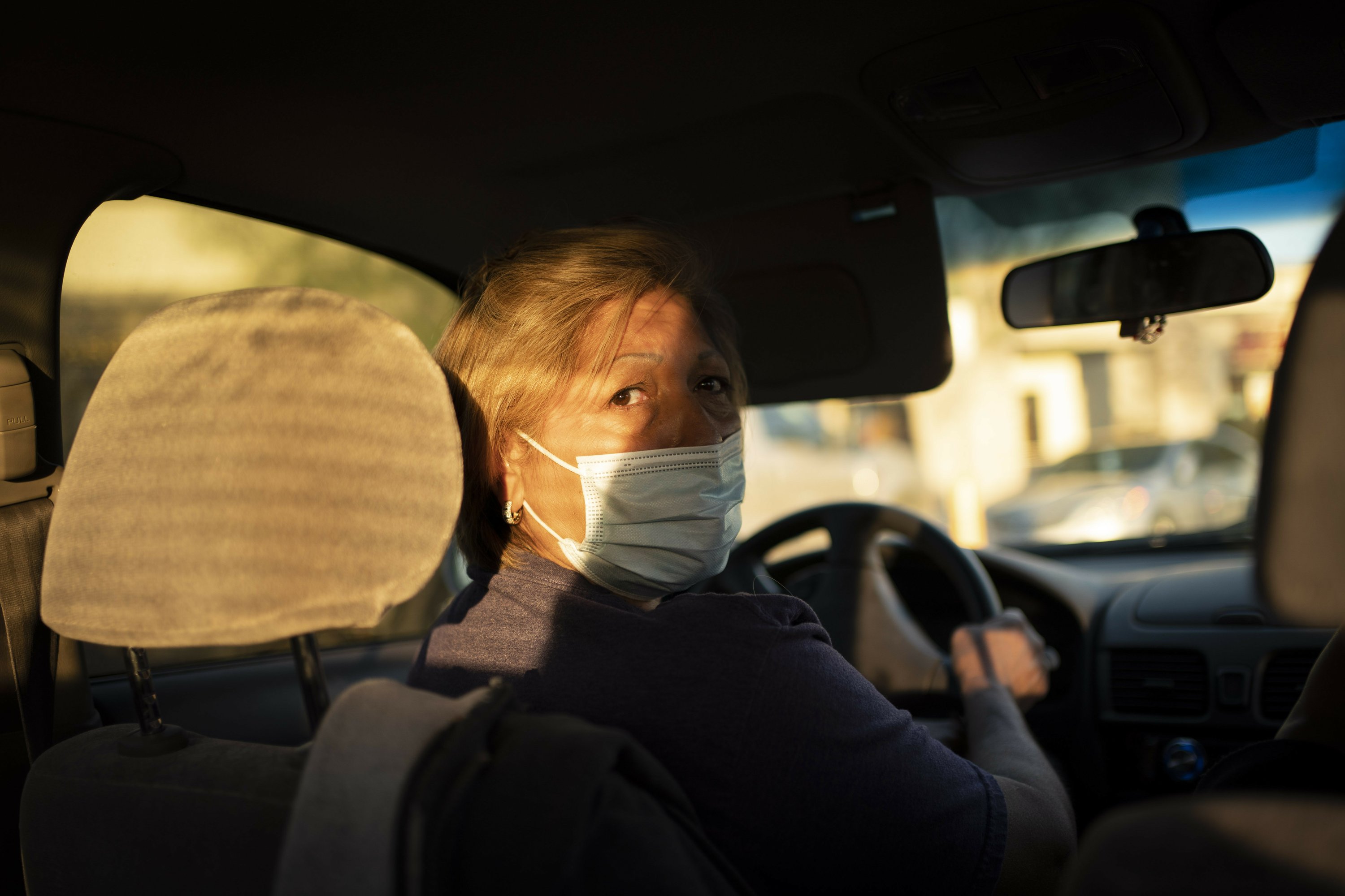 Norma Flores checks for traffic behind her as she drives to a grocery store near her home in Henderson, Nev., Tuesday, Nov. 10, 2020. Flores is a Mexican immigrant who spent two decades working as a waitress before COVID-19 descended and she lost her job. At night, she often lies awake, worrying about paying the rent, buying gas, getting enough food for her family. Image by Wong Maye-E / AP Photo. United States, 2020. Norma Flores checks for traffic behind her as she drives to a grocery store near her home in Henderson, Nev., Tuesday, Nov. 10, 2020. Flores is a Mexican immigrant who spent two decades working as a waitress before COVID-19 descended and she lost her job. At night, she often lies awake, worrying about paying the rent, buying gas, getting enough food for her family. Image by Wong Maye-E / AP Photo. United States, 2020.