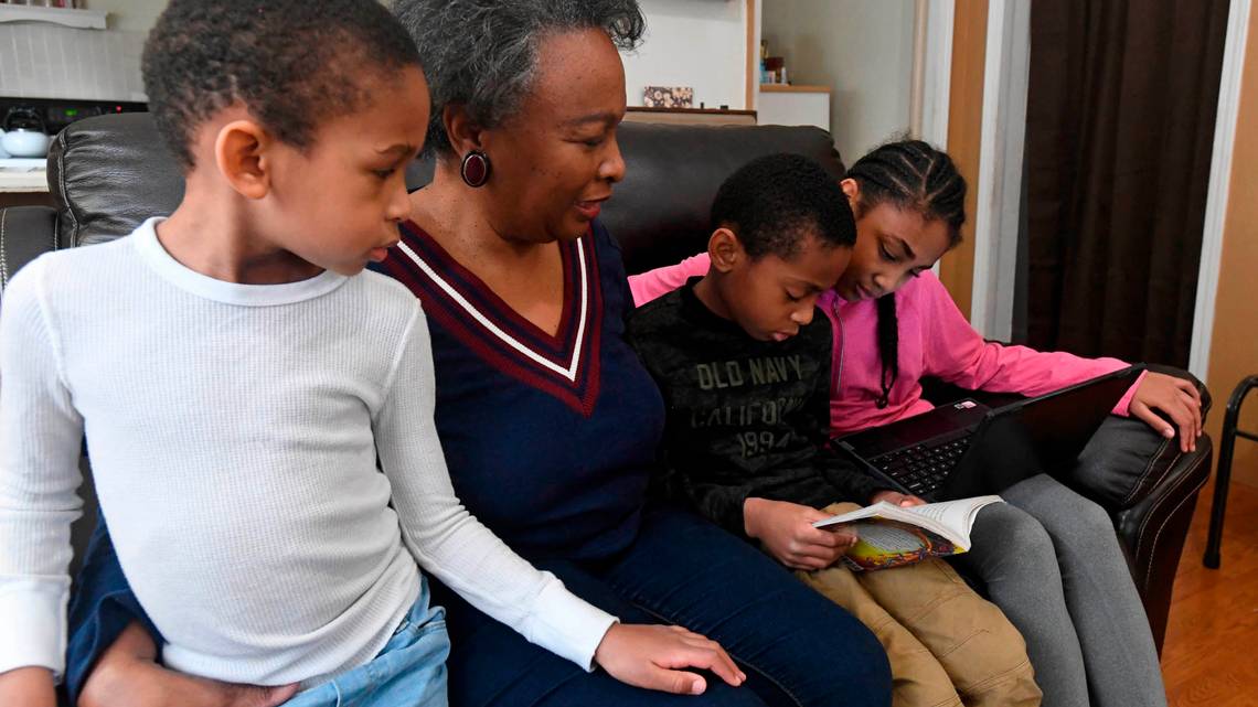 Regina Barrett, center, sits with her grandchildren Asa Barrett, left, 5, Hallie Barrett, 10, and Asher Barrett, 8, in her Monroe, NC home on Wednesday, February 10, 2021. Regina Barrett began juggling the roles of grandmother, caregiver and teacher to help out when the pandemic shutdown schools last year. Image by David T. Foster III. United States, 2021. Regina Barrett, center, sits with her grandchildren Asa Barrett, left, 5, Hallie Barrett, 10, and Asher Barrett, 8, in her Monroe, NC home on Wednesday, February 10, 2021. Regina Barrett began juggling the roles of grandmother, caregiver and teacher to help out when the pandemic shutdown schools last year. Image by David T. Foster III. United States, 2021.