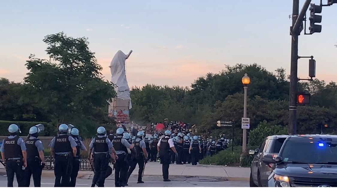 Dozens of police officers cross a street.