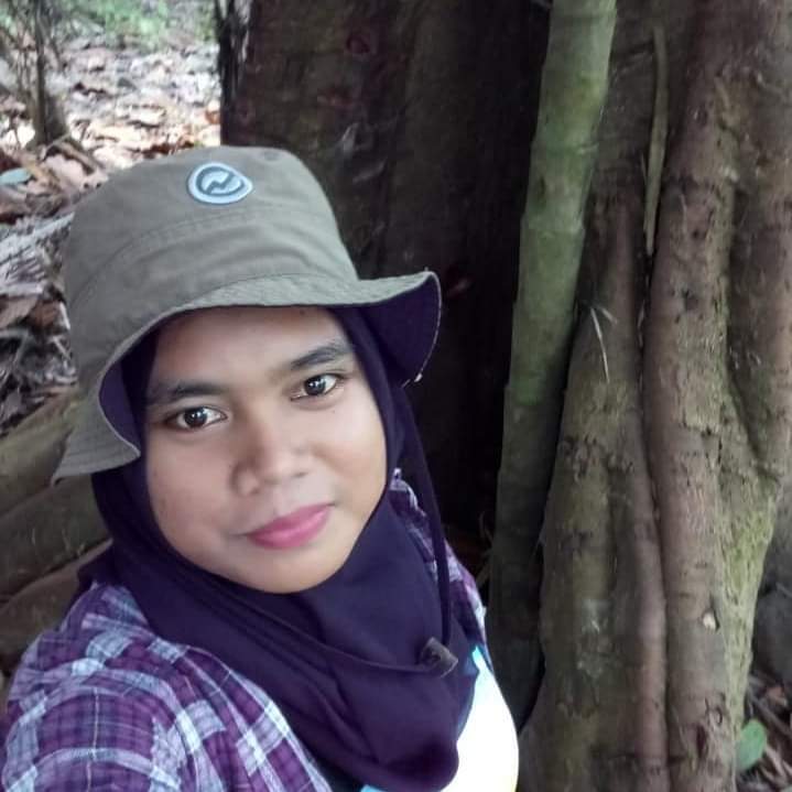 A person wears a cap, purple shirt, and a purple scarf.