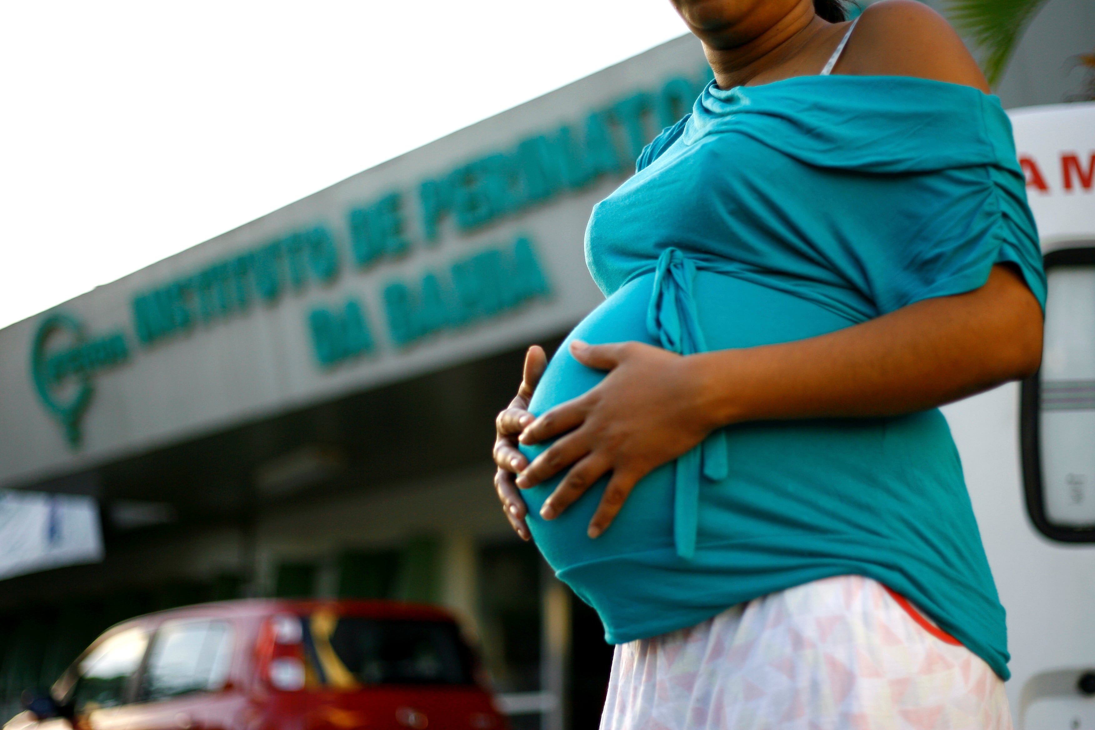 A pregnant person holds their swollen womb