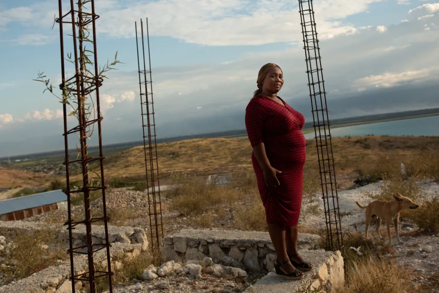 Carmen Cean, a.k.a. "Madame Roy," poses for a photo on a foundation near her home on a hilltop in the Village de Pecheur neighborhood of greater Canaan. Image by Allison Shelley. Haiti, 2019. Carmen Cean, a.k.a. "Madame Roy," poses for a photo on a foundation near her home on a hilltop in the Village de Pecheur neighborhood of greater Canaan. Image by Allison Shelley. Haiti, 2019.