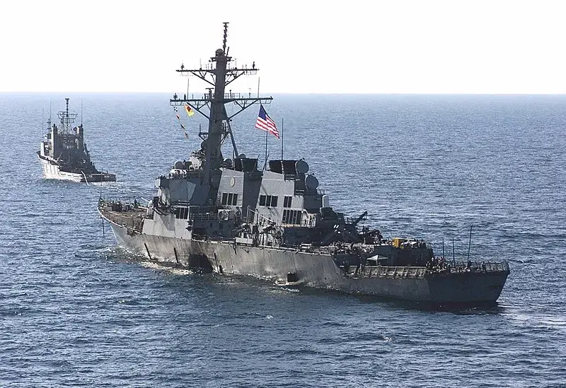 The USS Cole (DDG 67) is towed away from the port city of Aden, Yemen, into open sea by the Military Sealift Command ocean-going tug USNS Catawba (T-ATF 168) on Oct. 29. Image by Sgt. Don L. Maes, U.S. Marine Corps. Yemen, 2000. (Public Domain)