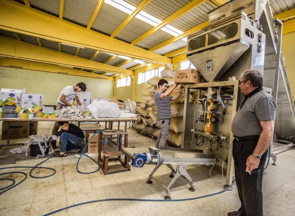 A young Syrian refugee packs tea boxes under a table in a Turkish factory near his refugee camp on the Turkey-Syria border.