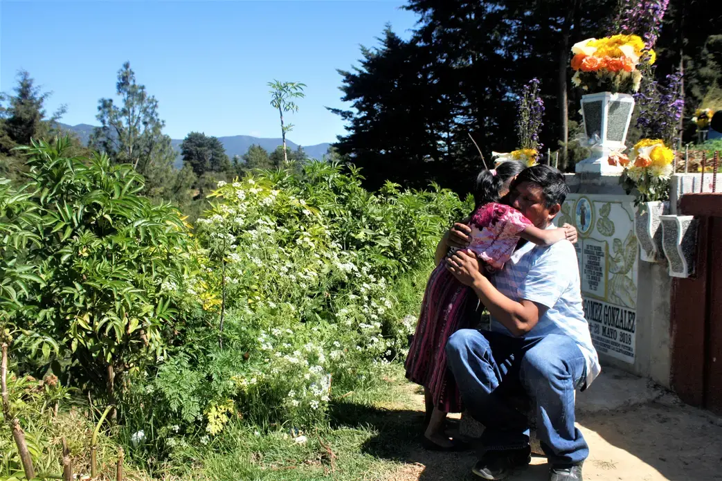 Gilberto Gomez-Gonzales hugs his youngest daughter during a visit to the cemetery where his eldest daughter, Claudia Gomez-Gonzalez, was laid to rest after she was killed by a U.S. Border Patrol agent in May and repatriated to her hometown of San Juan, Quetzaltenango, Guatemala. Image by Kristian Hernandez. Guatemala, 2018.