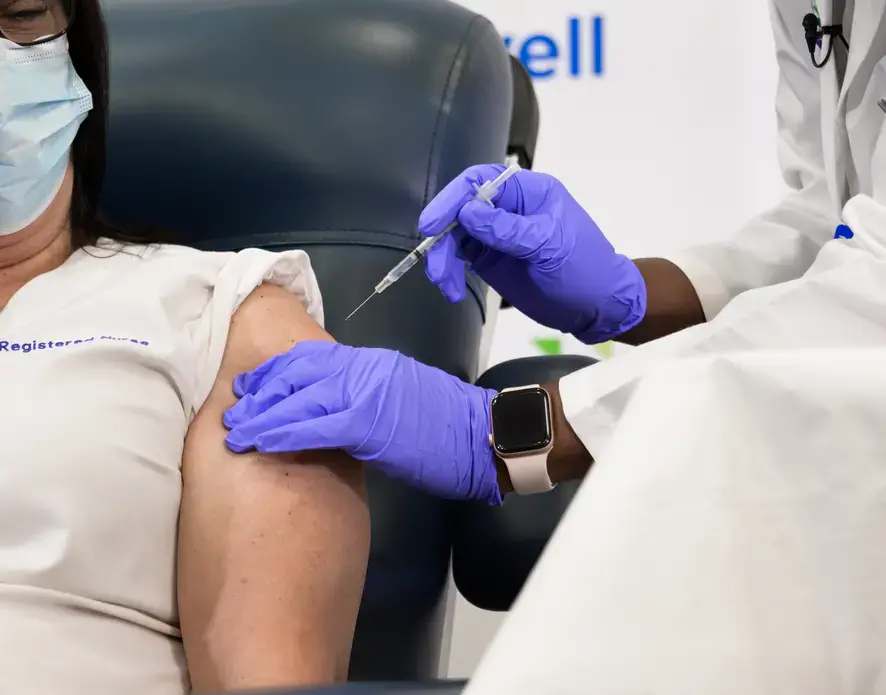 A medical worker administers the Pfizer-BioNTech COVID-19 vaccine to an ICU nurse at the Long Island Jewish Medical Center. Image by noamgalai / Shutterstock. United States, 2020.