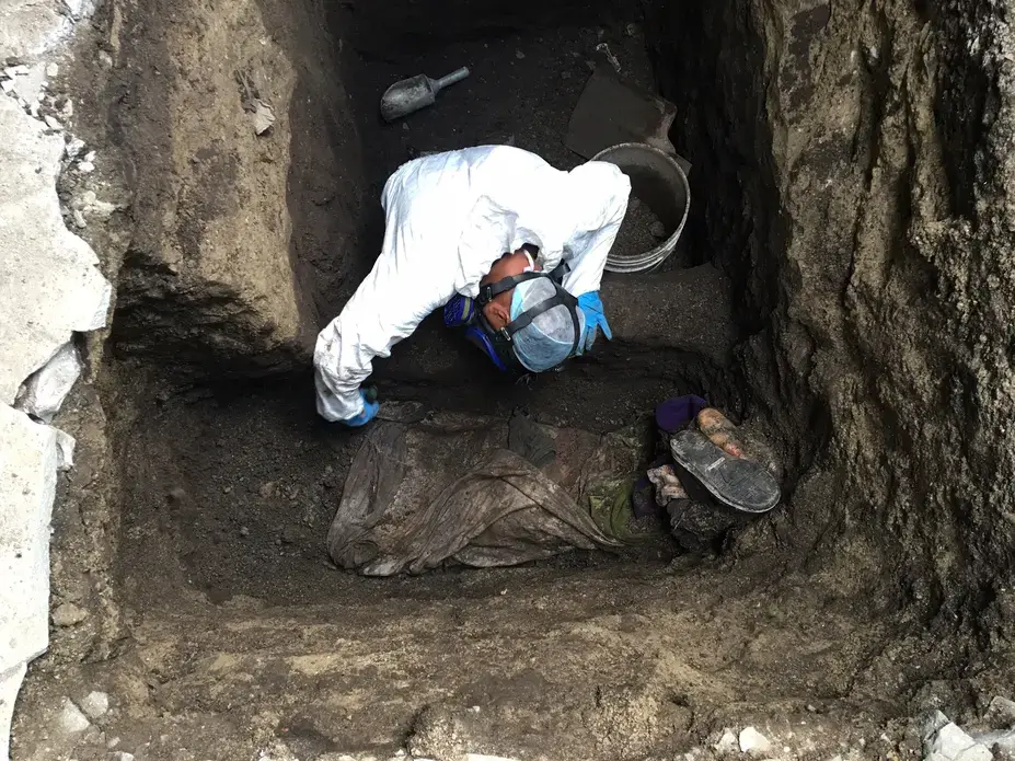Forensic criminologist Ticas Israel brushes the body of an unidentified man killed by gang members and buried in a hidden grave in Ilopango. Image by Jason Motlagh. El Salvador, 2016.