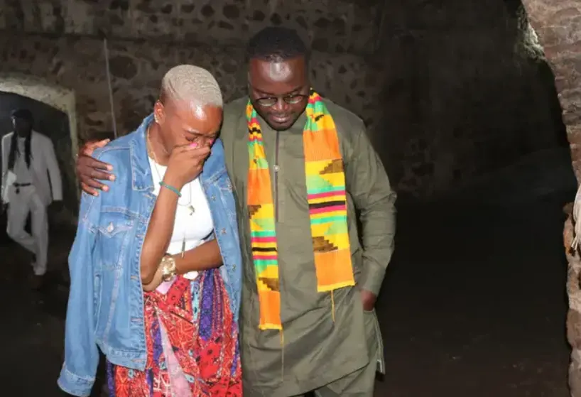 A tour guide comforts NAACP Youth and College Director Dena Loftin inside the Cape Coast Slave Castle on Ghana's coast. Africans captured by slave traders were herded inside small dungeons and endured horrendous conditions before being put on a ship to lands unknown. Those who died were thrown to the sharks; those who survived were sent across the sea in chains. Image by NAACP. Ghana, 2020.
