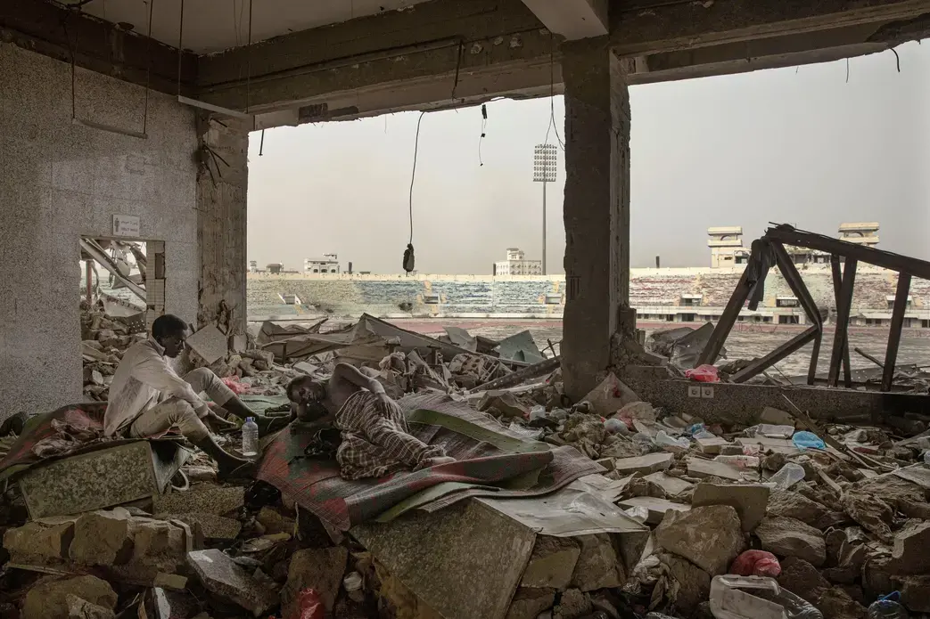 Ethiopian migrants take shelter in the "22nd May Soccer Stadium," destroyed by war, in Aden, Yemen. Image AP Photo/Nariman El-Mofty. Yemen, 2020.