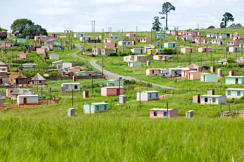 A village of brightly colored Mandela Houses in Zulu Village, Zululand, South Africa. Image by Joseph Sohm / Shutterstock. South Africa, 2019.