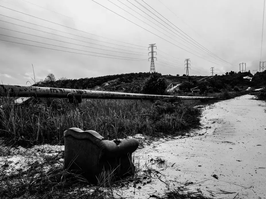 ENVIRONMENTAL RISK. An abandoned sofa sits near the oil pipeline in Kandis. Miles of crude oil and gas pipeline and hectares of palm trees run alongside a road in Kandis, Riau, Indonesia on June 27, 2018. Image by Xyza Cruz Bacani.