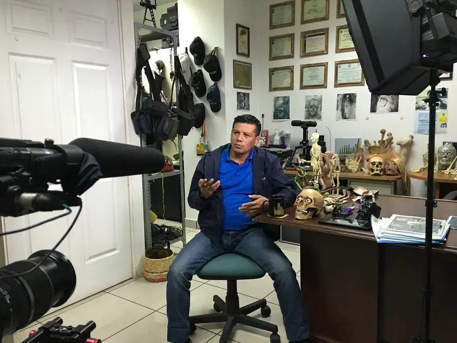 Forensic criminologist Israel Ticas speaks to media in the San Salvador office where he keeps grisly mementos from the crime scenes he has worked. Image by Jason Motlagh.