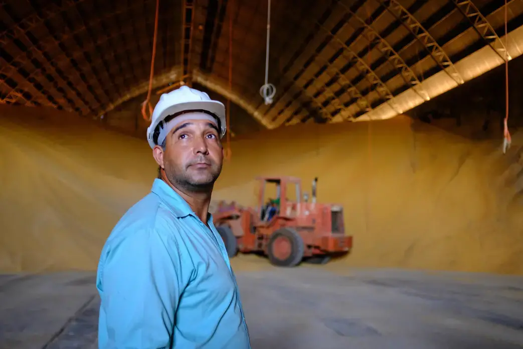 A worker at Grupo Vale do Verde looks on as grain is moved at one of its many facilities in the state of Mato Grosso. Big Ag in Brazil wants to see better transport options, including the construction of a railway, the Ferrogrão — “the grain train” — that would cut across the jungle. Image by Melissa Chan. Brazil, 2019.