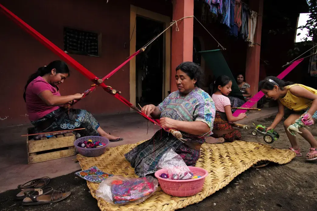 Maria de Jesus Lopez Pérez, 62, (center) is the matriarch of a clan of weavers living in a cramped compound in San Antonio Aguas Calientes. To provide the family of 45 with a normal Sunday meal, all the women hover around fires in one corner of the compound. Image by Lynn Johnson. Guatemala, 2017.