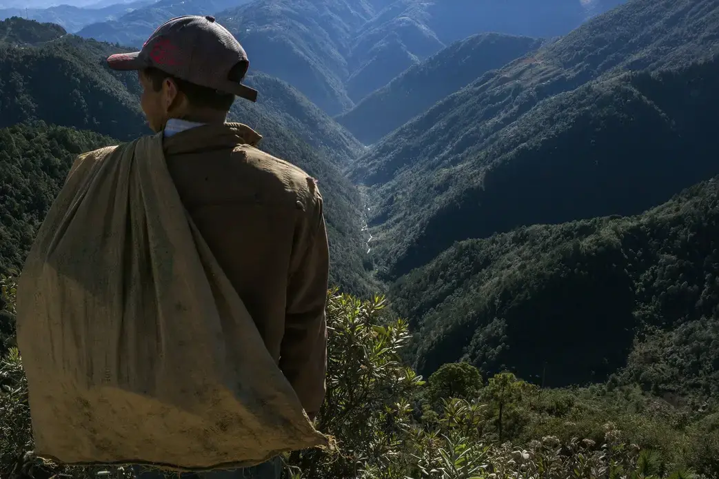 A man pauses above the Captzin River, in the highlands of western Guatemala, on his way home from collecting recyclable materials. Image by Mauricio Lima. Guatemala, 2019.