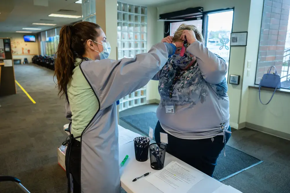 A staff member at Unity Care NW has her temperture checked and signs off on her lack of COVID-19 symptoms prior to beginning her shift at the clinic. Image by Gregg Brekke / Shutterstock. United States, 2020.
