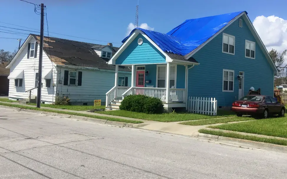 A home in Beaufort, North Carolina awaits roof repair. The tarp protects the home from further water damage. A shortage of contractors following the storm left many people waiting months for repairs. Image by Erika Layko. United States, 2018.
