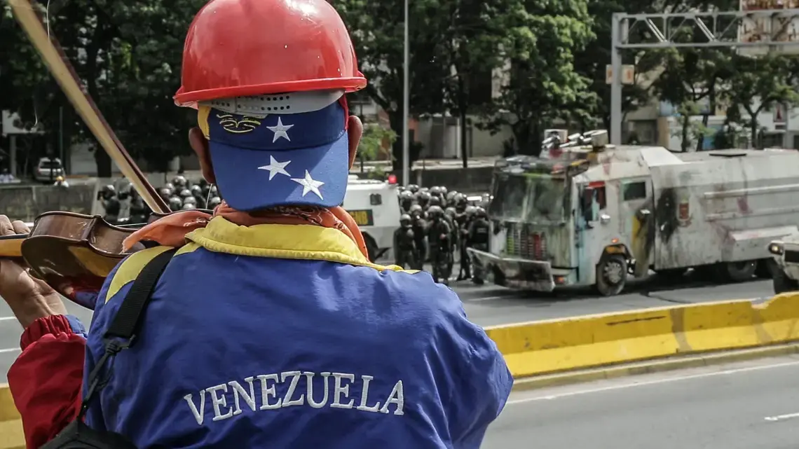 A violinist plays in front of Venezuelan National Guard during an anti-government protest in Caracas. Image by Bruno Federico. Venezuela, 2017.