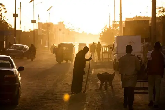A man sweeps dust off the street at dusk in Agadez, Niger. Image by Joe Penney. Niger, 2018. 