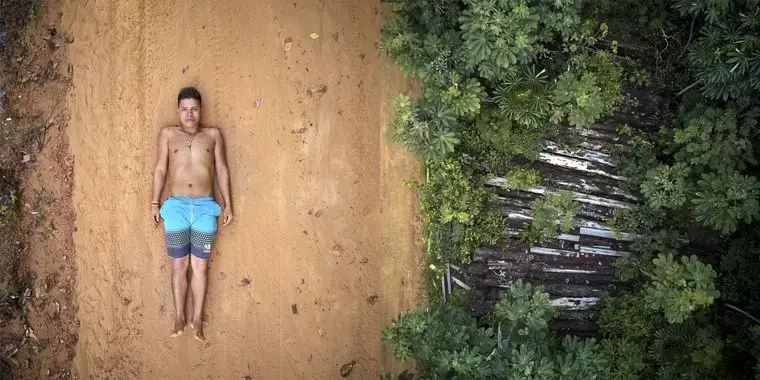 Ednei poses on the tracks left by the trucks used to transport wood that pass through the borders of his territory. Right: what's left of 26 trees destroyed by illegal lumberjacks in indigenous Maró territory. Image by Pablo Albarenga. Brazil, 2019.