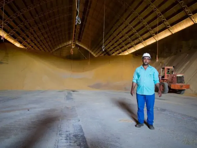 Um trabalhador em Sinop mostra um enorme depósito de grãos, em que a soja e o milho são armazenados em temperatura e umidade controladas para, paulatinamente, ser transportados por caminhão e depois exportados. Imagem de Heriberto Araújo. Brasil, 2019.