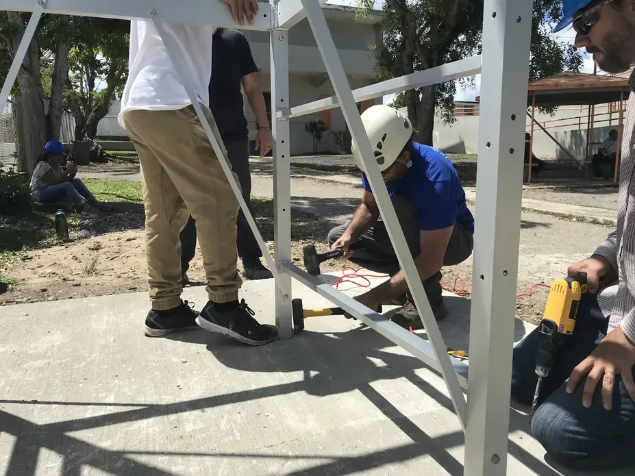Ludgardo Vendrell of the Rayo De Luna organization&nbsp;secures the water tower to its cement base on the Escuela Espino Elementary School campus. Image by Tomas Woodall Posada. United States, 2018.