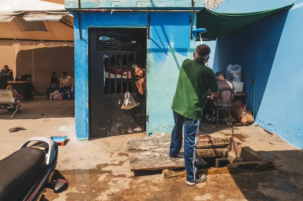 Prisoners pass the time playing dominos in an outdoor common area at Ana Maria Campos I Prison, Maracaibo, while others watch movies, read old magazines or write notes. Image by Ana María Arévalo. Venezuela, 2018. 