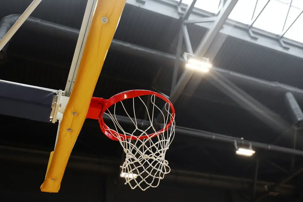 Basketball hoop in the sports center against the dark ceiling. Image by Andrew Makedonski / Shutterstock.