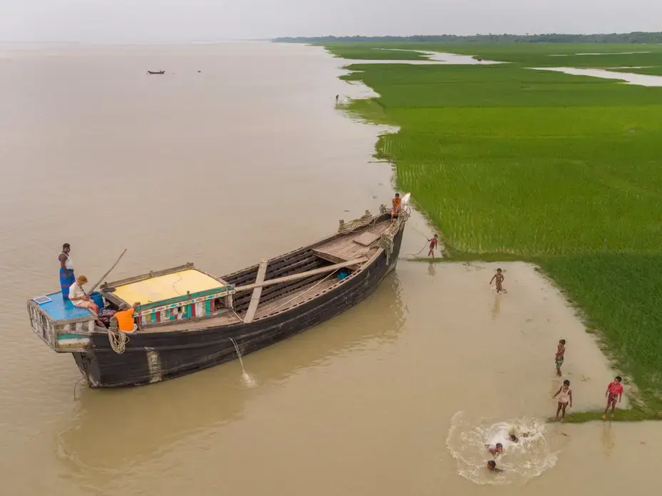 The photographer George Steinmetz spent a year traveling the world to document climate change. In this image, from Bangladesh in Sept. 2017, he is in the boat flying the drone that took this photo. Image by George Steinmetz. Bangladesh, 2017.