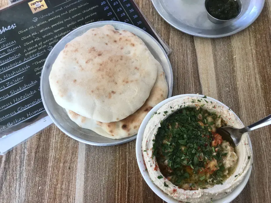 Hummus, pictured here, is more than just a snack. It's considered "worker's food." Historically, it was used to feed those with manual labor jobs who needed a filling breakfast that would get them through an exhausting work day. Today, many hummus establishments continue to exclusively serve the blended mix of tahini, chickpea, olive oil and lemon juice—opening early in the morning and closing once they run out. Image by Carly Graf. East Jerusalem, 2019.