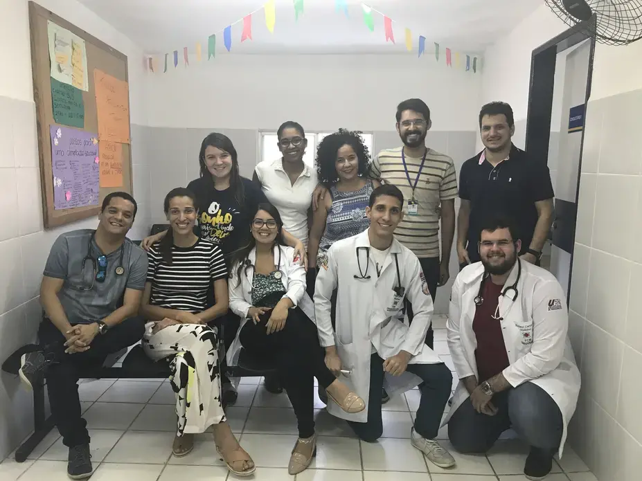 The multidisciplinary healthcare team at the USF&nbsp;in Córrego do Eucalipto. Each USF is supposed to be staffed with a physician, nurse, nurse assistant, and multiple community health agents, in addition to a primary care support team that may include nutritionists, psychologists, social workers, and others. Talita Rodrigues, 26, resident psychologist, is featured in the center in a patterned tank top, with Gerson da Silva, 25, the resident sanitarian, to her immediate right. Image by Poonam Daryani. Brazil, 2017.