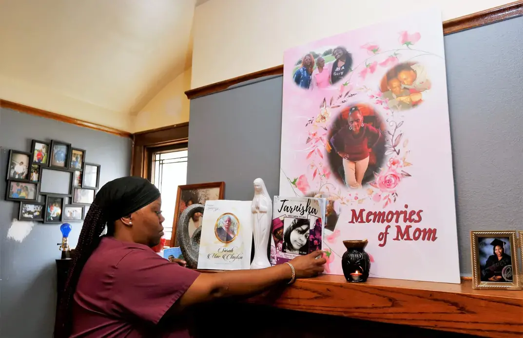 Wyconda Clayton looks at photos of her late mother on the mantle in her Milwaukee duplex. Image by Pat A. Robinson. United States, 2020.