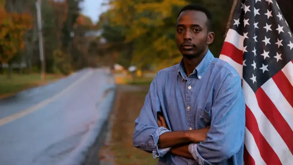 Abdi Nor Iftin in front of the U.S. flag. Image by Leo Hornak. United States, undated.