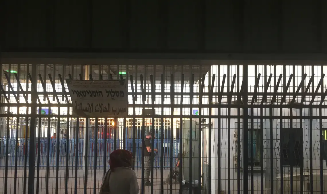 Israeli private security guards chat with Israel Defence Force (IDF) soldiers behind the bars at Qalandia checkpoint. Image by Matt Kennard. West Bank, 2016.