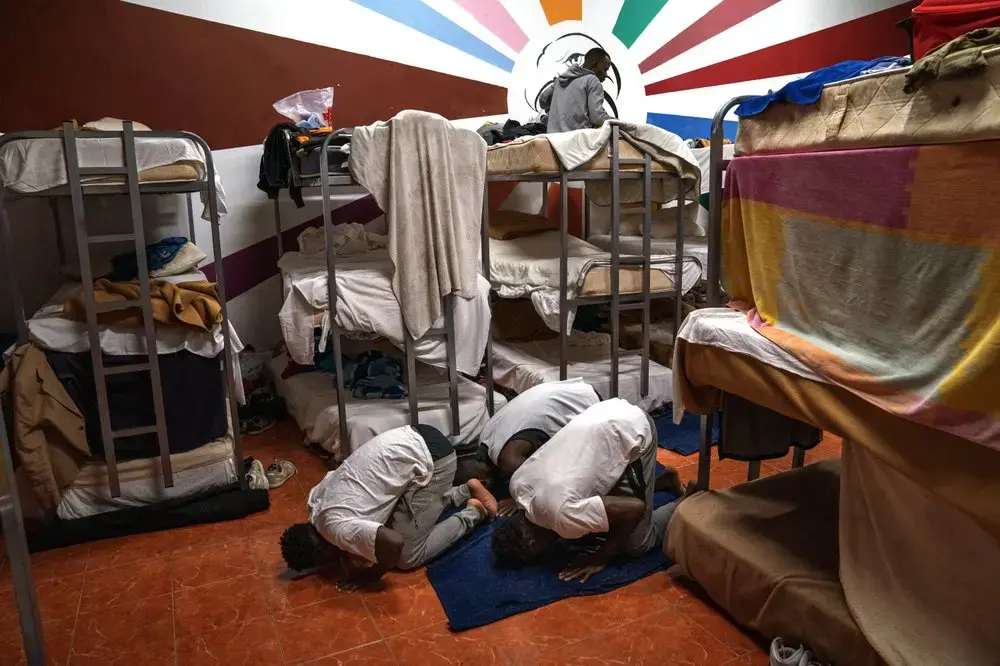 Asylum-seekers pray next to their beds at the Modern Christian Mission Church in Fuerteventura, one of the Canary Islands, Spain, on Saturday, Aug. 22, 2020.&nbsp;Image by Emilio Morenatti/AP Photo. Spain, 2020.