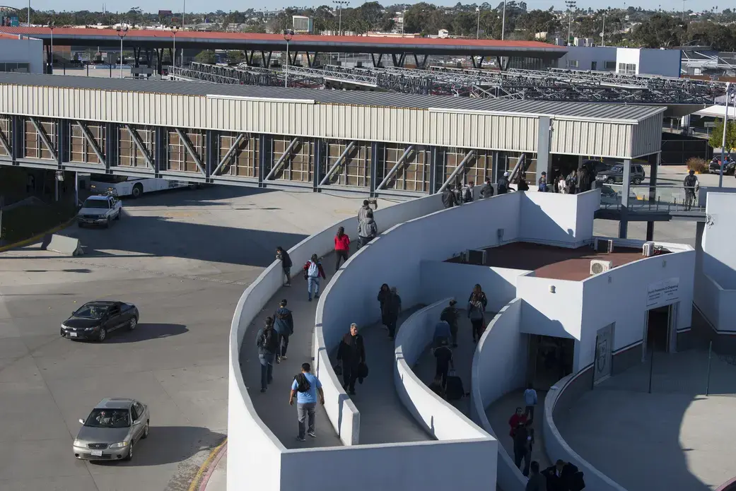 Motorists make their way into Mexico as pedestrians prepare to cross into the United States on foot over the main border crossing in Tijuana, El Chaparral, on Dec. 1. Image by Amanda Cowan. Mexico, 2019.