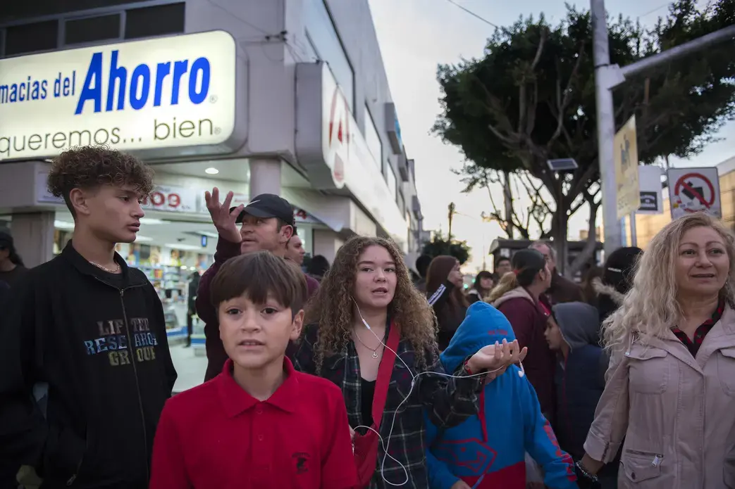 Members of the family express opposite points of view as they try to choose the best route through an intersection in heavy traffic while visiting downtown Tijuana on Saturday, Nov. 30, 2019. Family members are Raymond, 15, Edward, 12, Kennedy, 16, Rayma, 10, and Enedis. Image by Amanda Cowan. Mexico, 2019.
