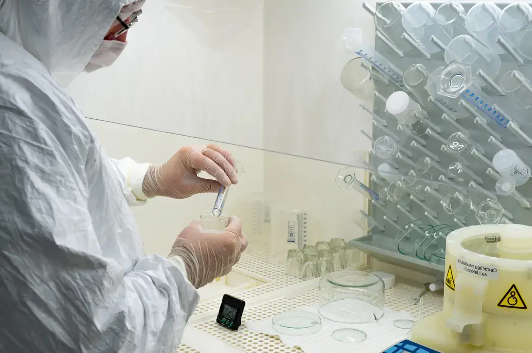 A scientist in a laboratory studying and analyzing samples for vaccines with glass vials. Image by  Michele Ursi / Shutterstock. Lithuania, 2020.
