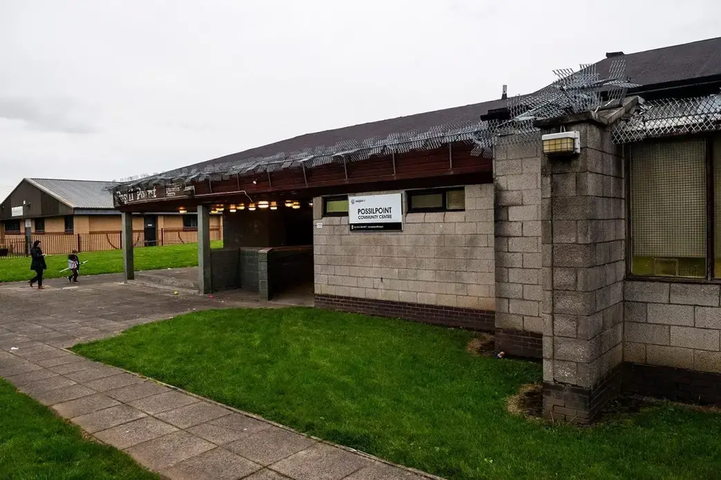 A woman and a young child walk toward the entrance of the Possilpoint Community Centre, Glasgow, Scotland. Image by Michael Santiago. United Kingdom, 2019.