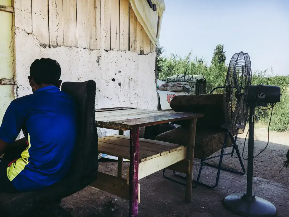 An unaccompanied minor sits in front of a migrants' shack in Marathona Village. Image by Divya Mishra. Greece, 2018.