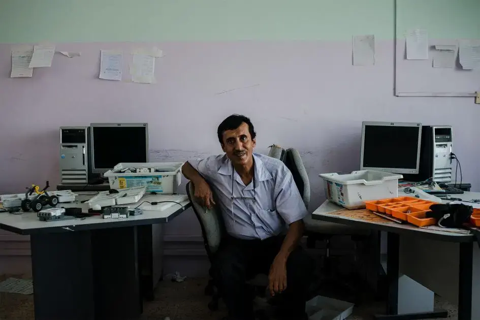 Fathi sits in the computer and robotics lab in the school where he teaches English. Image by Alex Potter. Yemen, 2018.