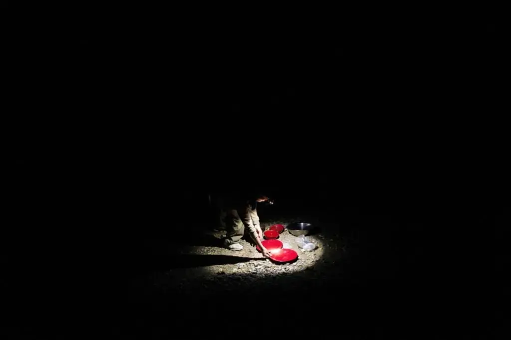 Sally Kwan washes the dishes after dinner by the water's edge at Spencer Lake in T3 R5, in the Unorganized Territories of Maine, on Aug. 3, 2019. Image by Michael G. Seamans. United States, 2019.