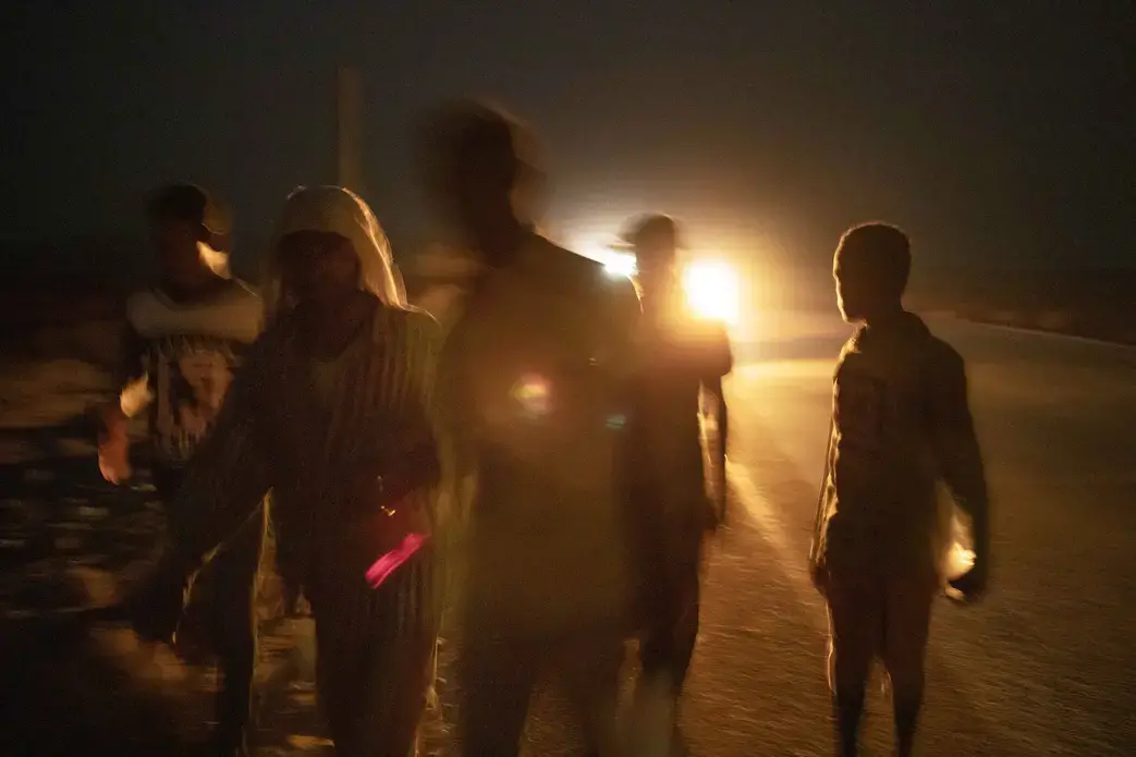 Ethiopian migrant Mohammed Eissa, second left, walks on a highway with boys he met on the way, about 50 kilometers (31 miles) from Djibouti, July 12, 2019. This was his third attempt to reach Saudi Arabia to find work; the previous trips ended in deportation. Eissa had left behind his wife, nine sons, and a daughter. His wife cares for his elderly father. His children work the farm growing vegetables, but harvests are unpredictable: 'If there's no rain, there's nothing.' Image by AP Photo/Nariman El-Mofty. Ethiopia, 2019.