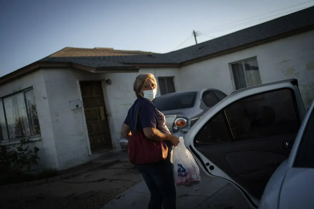 Norma Flores carries her groceries into her home in Henderson, Nev., Tuesday, Nov. 10, 2020. Image by Wong Maye-E / AP Photo. United States, 2020.