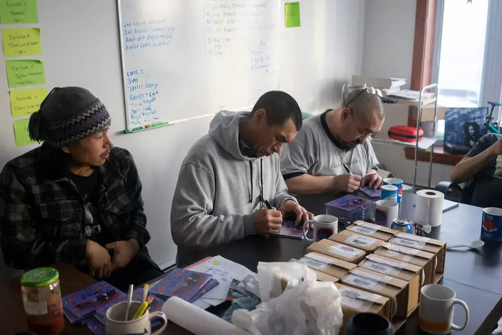 Band members from Northern Haze sign CD covers. Image by Nick Mott. Canada, 2018.